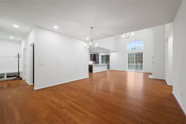 unfurnished living room featuring a chandelier, recessed lighting, baseboards, and wood finished floors