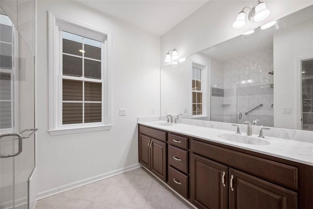 bathroom featuring double vanity, a stall shower, a sink, and baseboards