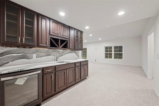 kitchen featuring dark brown cabinets, a sink, glass insert cabinets, and light colored carpet