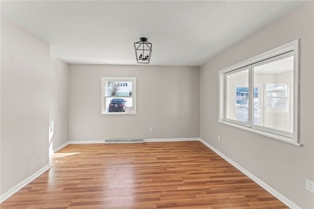 unfurnished room featuring a chandelier and light hardwood / wood-style floors