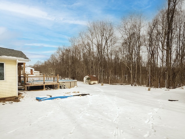 yard layered in snow with a shed and a deck