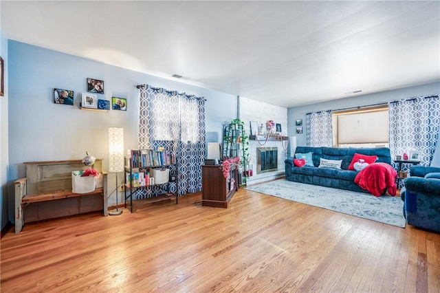 living room featuring hardwood / wood-style flooring and a stone fireplace