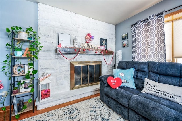 living room featuring wood-type flooring and a stone fireplace