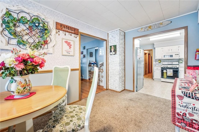 dining space with ornamental molding and light colored carpet