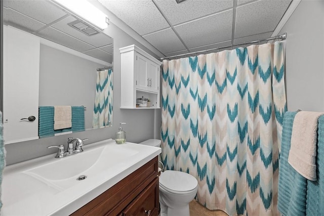 bathroom featuring toilet, vanity, a shower with curtain, and a drop ceiling