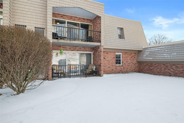 snow covered rear of property featuring a balcony