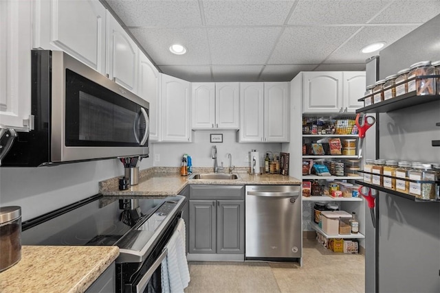 kitchen with white cabinetry, stainless steel appliances, a drop ceiling, and sink