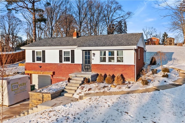 single story home featuring a garage, brick siding, a shingled roof, and a chimney