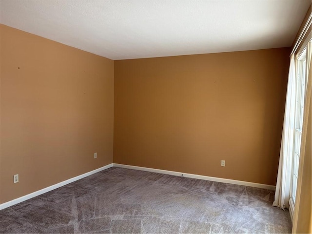 spare room featuring carpet floors and baseboards