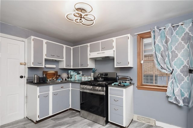 kitchen featuring light hardwood / wood-style floors, stainless steel gas range oven, and gray cabinetry