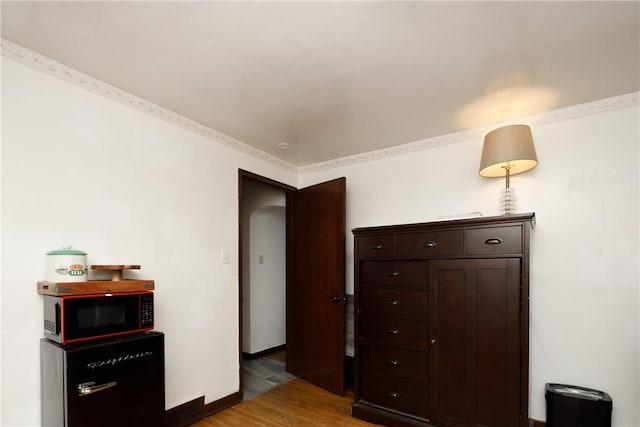 bedroom with fridge and hardwood / wood-style flooring