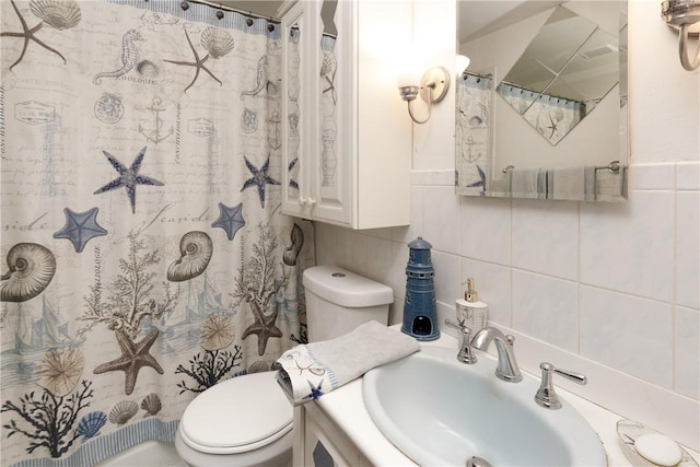 bathroom with vanity, tile walls, toilet, and walk in shower