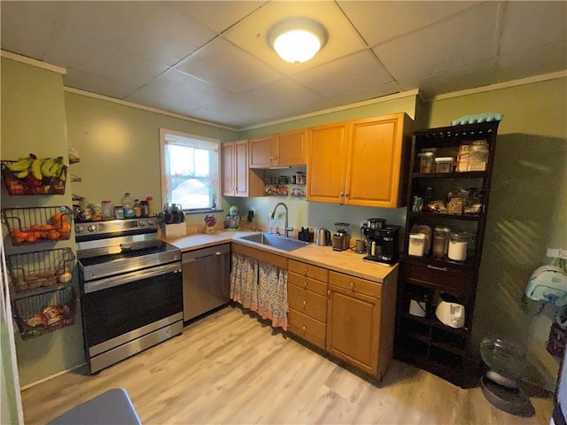 kitchen with appliances with stainless steel finishes, light hardwood / wood-style flooring, a paneled ceiling, crown molding, and sink