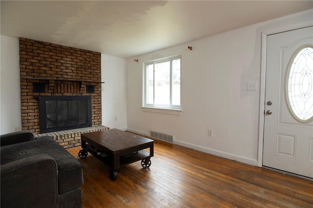 living room featuring dark wood-type flooring and a brick fireplace