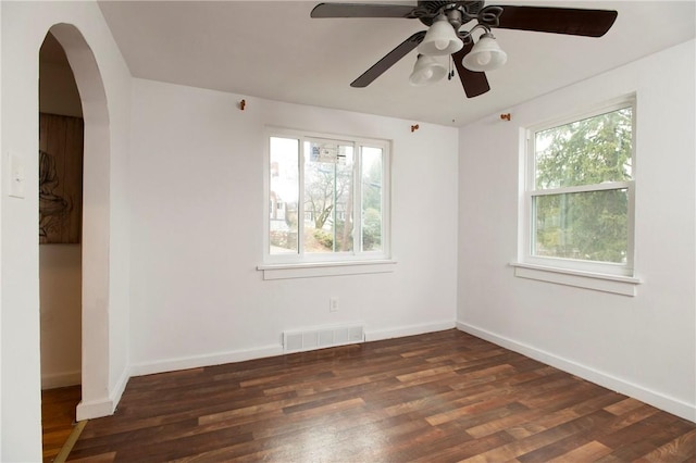 empty room featuring ceiling fan, plenty of natural light, and dark hardwood / wood-style flooring