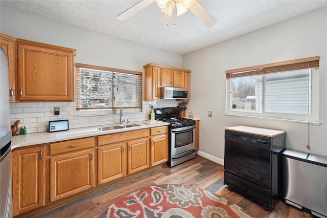 kitchen featuring stainless steel appliances, light countertops, decorative backsplash, wood finished floors, and a sink