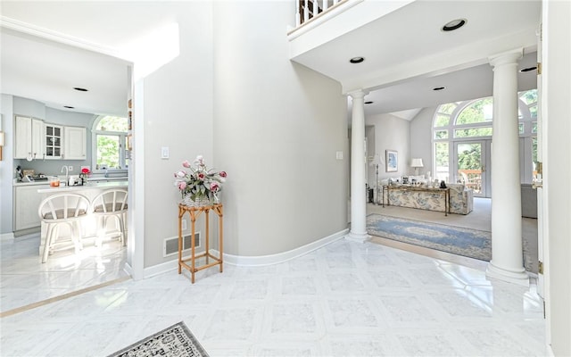 foyer featuring baseboards, vaulted ceiling, decorative columns, and visible vents