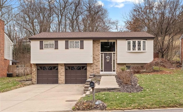 raised ranch with a garage, brick siding, a front lawn, and driveway