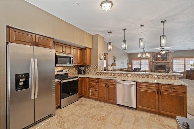 kitchen with sink, stainless steel appliances, kitchen peninsula, decorative backsplash, and hanging light fixtures