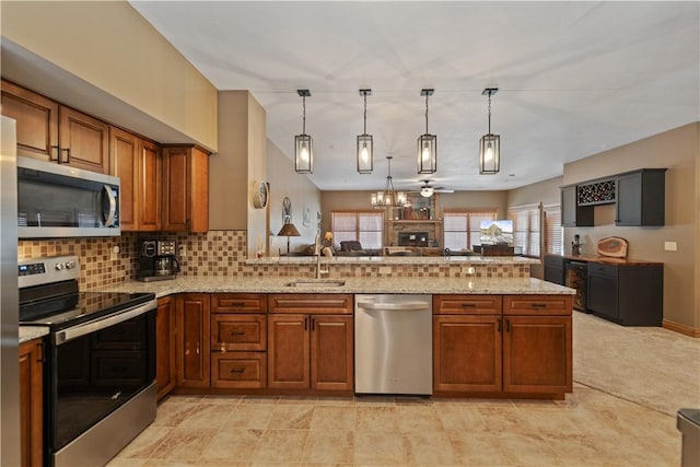 kitchen with pendant lighting, backsplash, kitchen peninsula, appliances with stainless steel finishes, and sink