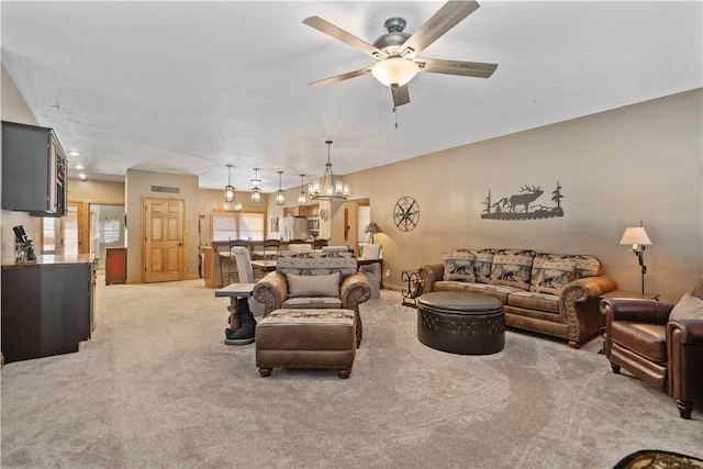 carpeted living room featuring ceiling fan with notable chandelier