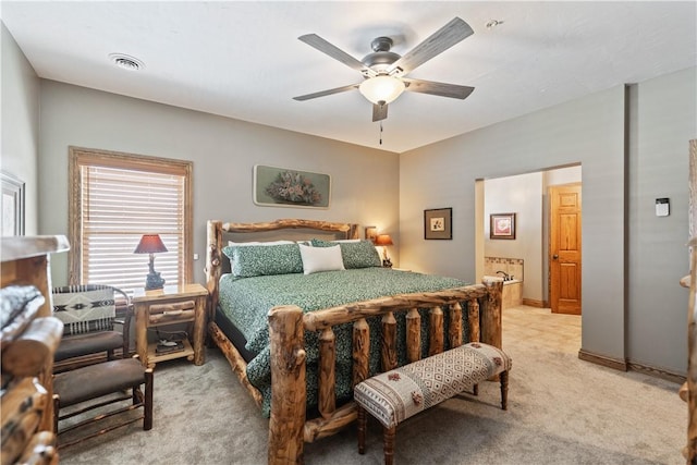 bedroom with light colored carpet, ceiling fan, and connected bathroom