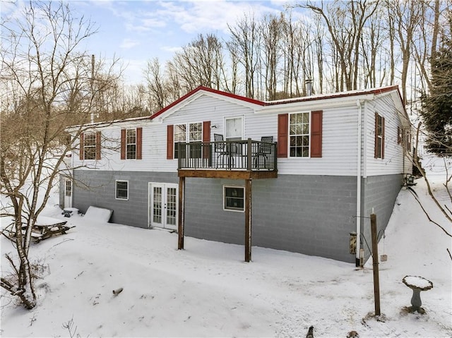 snow covered house featuring french doors and a deck