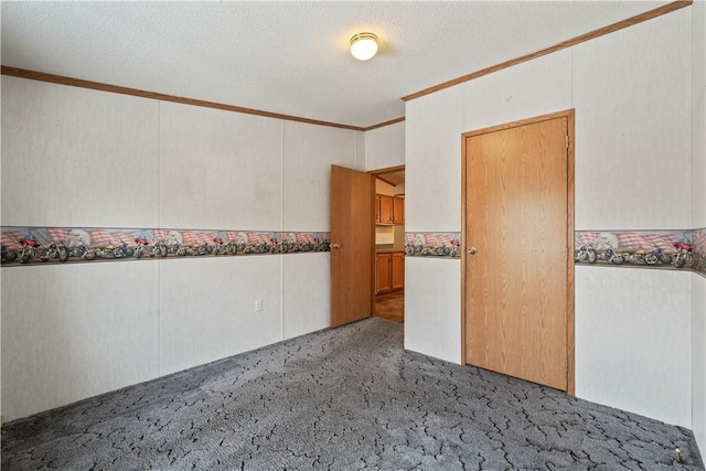 carpeted spare room with a textured ceiling and crown molding