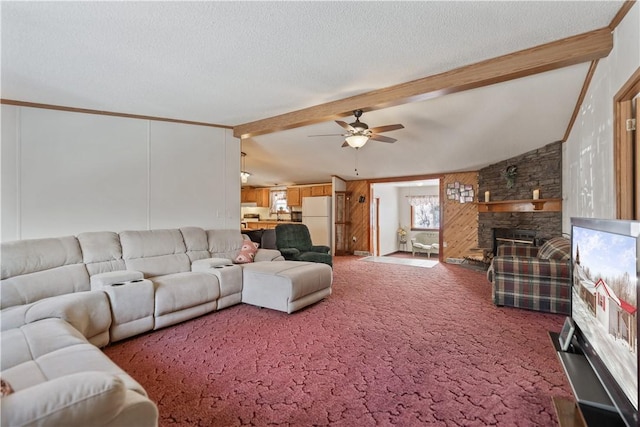 carpeted living room featuring a stone fireplace, a textured ceiling, lofted ceiling with beams, and ceiling fan