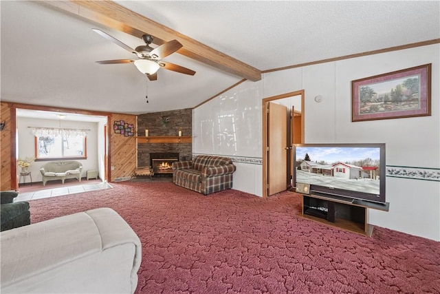 carpeted living room with ceiling fan, lofted ceiling with beams, a textured ceiling, a stone fireplace, and crown molding