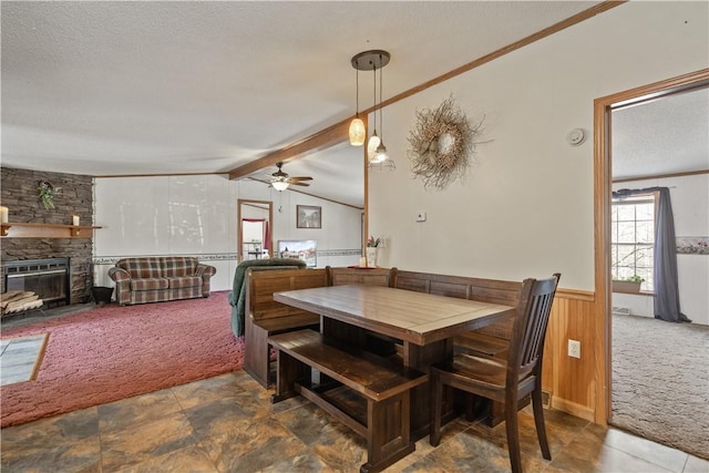 dining room with wood walls, a textured ceiling, vaulted ceiling with beams, and carpet