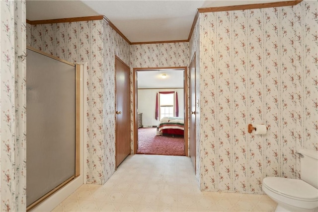 bathroom featuring toilet, crown molding, and a shower with door