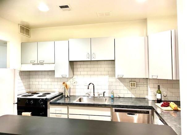 kitchen with dark countertops, white cabinetry, a sink, black range with electric cooktop, and dishwasher