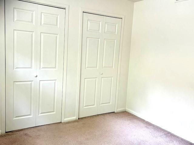 unfurnished bedroom with light carpet, visible vents, and baseboards