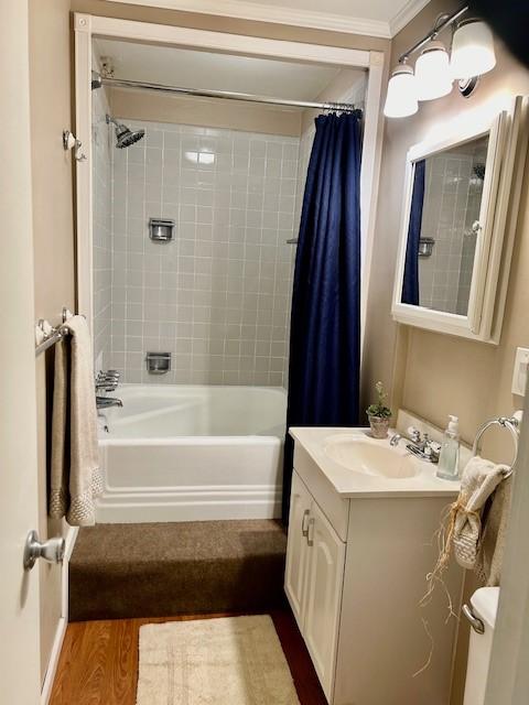 full bath with crown molding, wood finished floors, vanity, and shower / bathtub combination with curtain