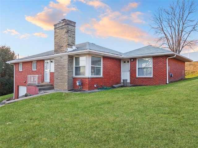 view of front of home featuring an attached garage, a front lawn, and brick siding