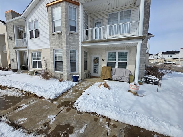 view of property with a balcony and brick siding