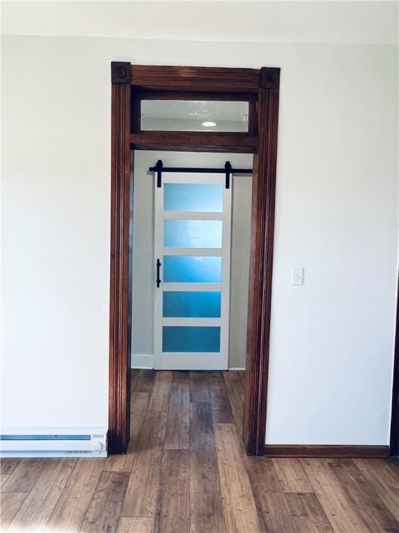 interior space featuring baseboards, a barn door, and wood finished floors