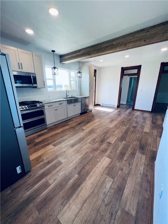 kitchen with dark wood-style floors, white cabinetry, appliances with stainless steel finishes, and pendant lighting