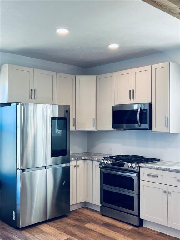 kitchen with stainless steel appliances, white cabinetry, and dark wood-type flooring