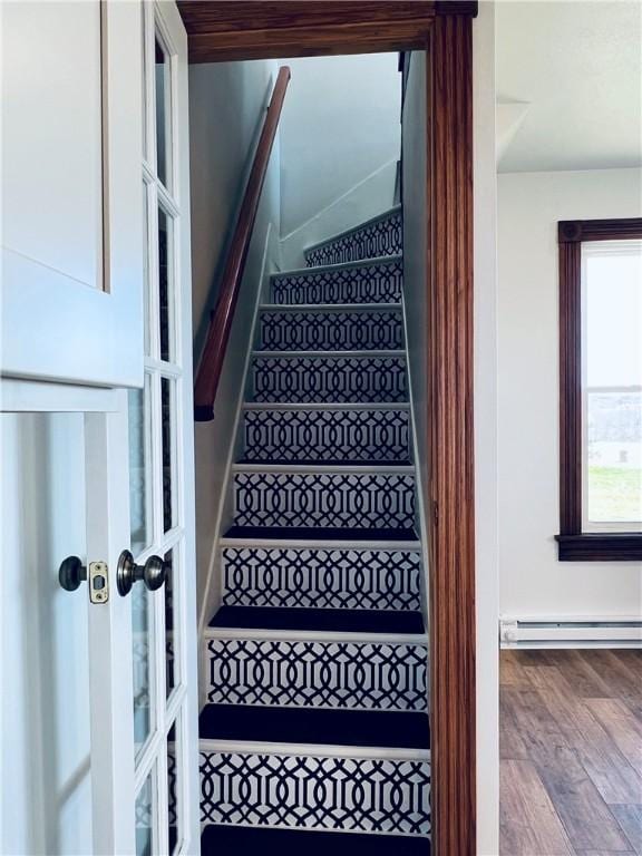 staircase with a baseboard radiator and wood finished floors