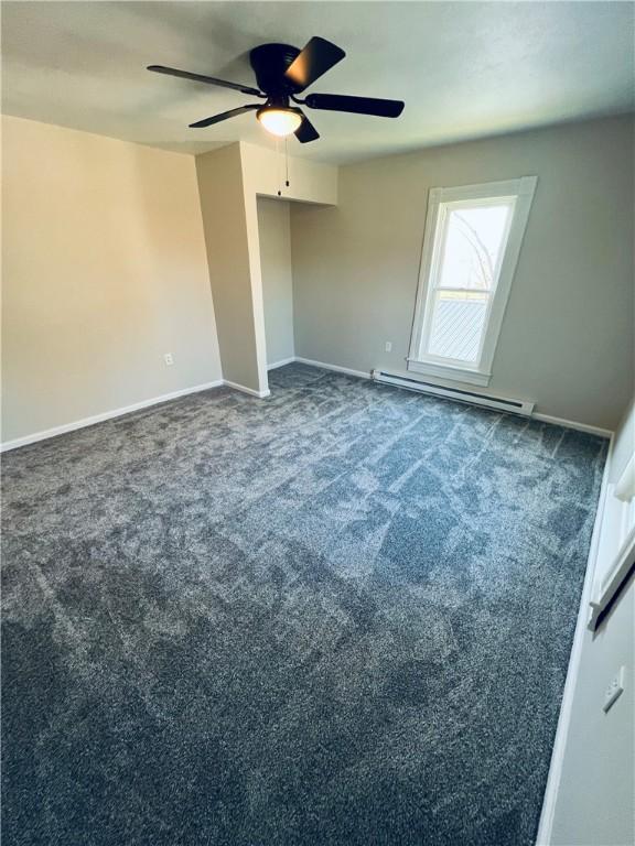 unfurnished bedroom with ceiling fan, baseboards, baseboard heating, and dark carpet