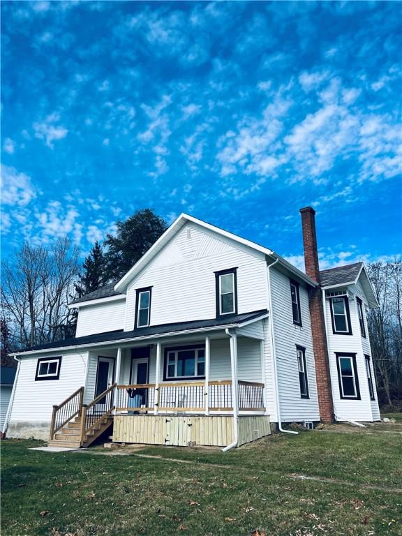 view of front of house with a porch, a chimney, and a front yard