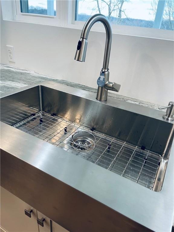 interior details with a sink, white cabinets, and light countertops