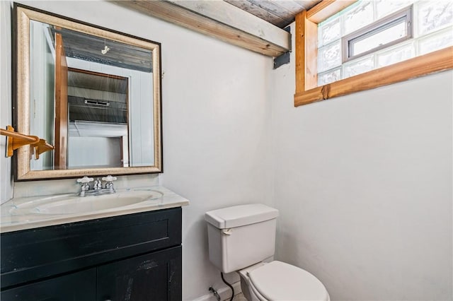 half bathroom featuring baseboards, vanity, and toilet