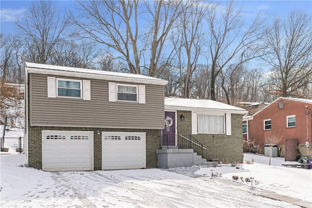 split level home with an attached garage, fence, and brick siding