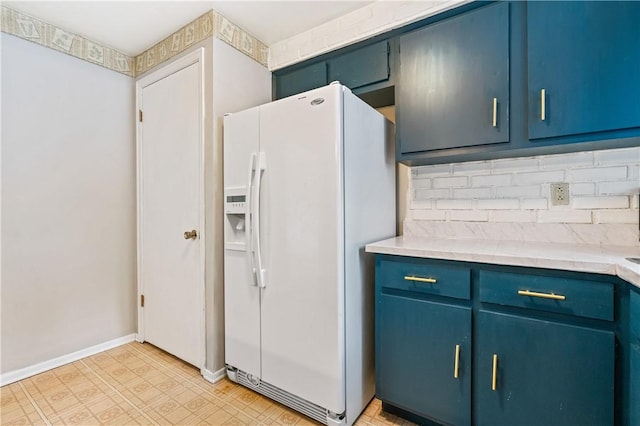 kitchen featuring tasteful backsplash, white refrigerator with ice dispenser, blue cabinets, light countertops, and baseboards