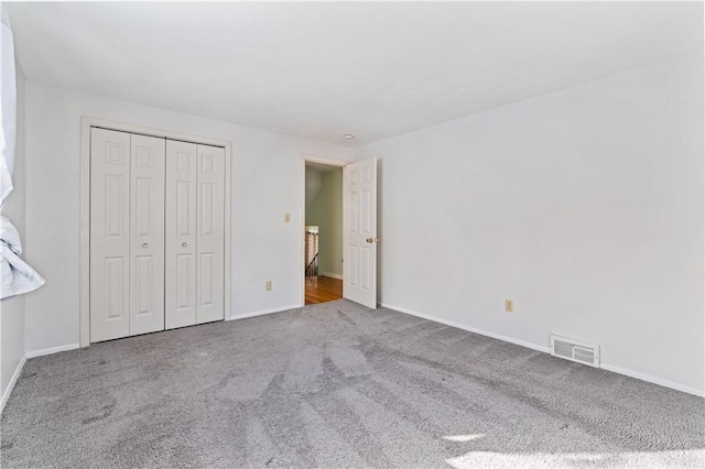 unfurnished bedroom with baseboards, a closet, visible vents, and carpet