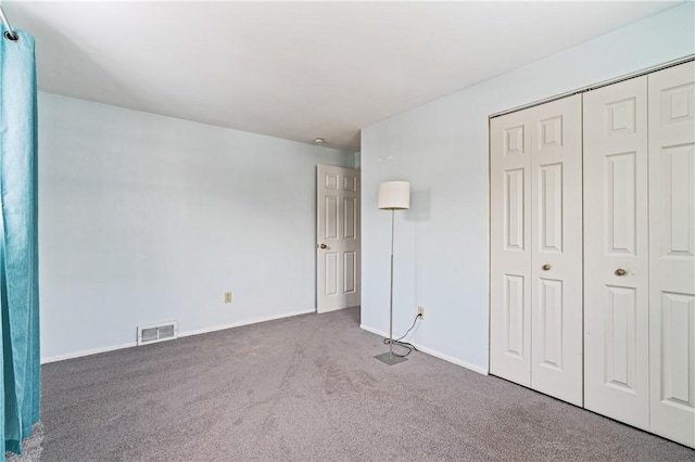 unfurnished bedroom featuring a closet, carpet floors, visible vents, and baseboards