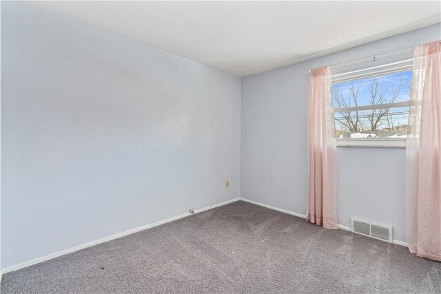 empty room with baseboards, visible vents, and carpet
